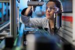 Woman examining machine parts on production line